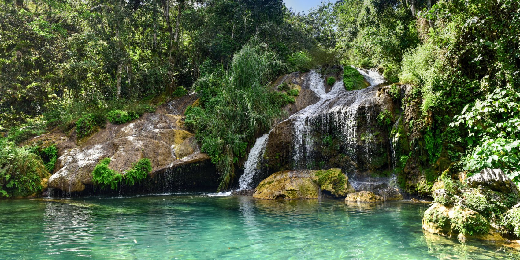 Waterfall going into a crystal clear pool in Desembarco del Granma National Park on a sunny day