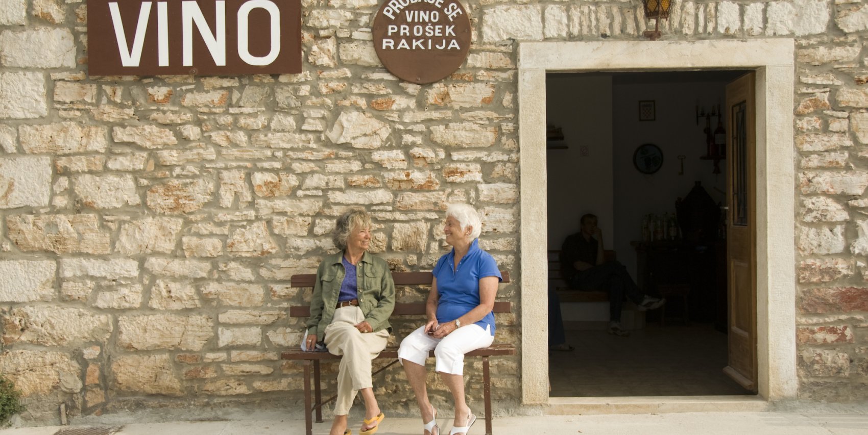 Two women sitting outside of a restaurant in Croatia smiling and laughing at one another