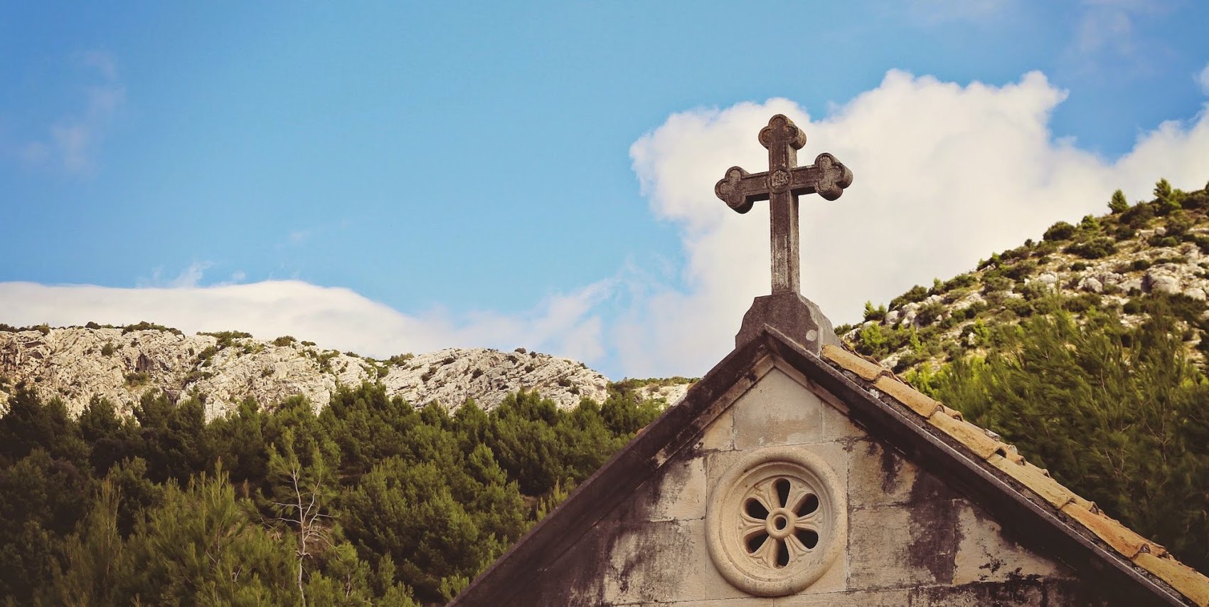 A stone cross at the top of an a-frame church in Croatia