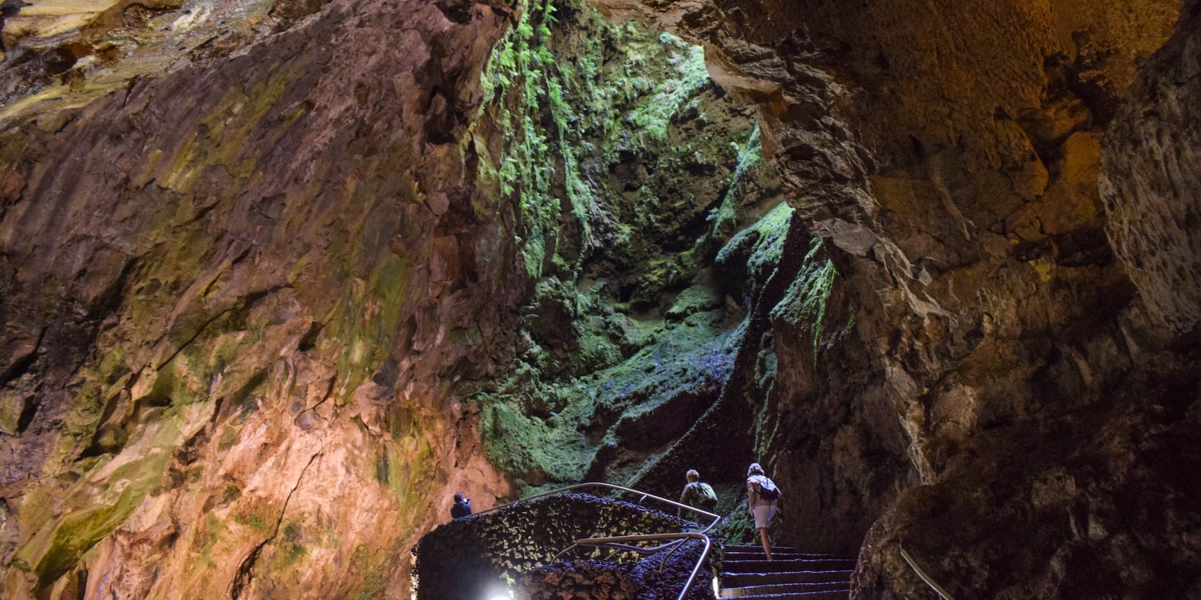 Two people exploring a cave in Azores.