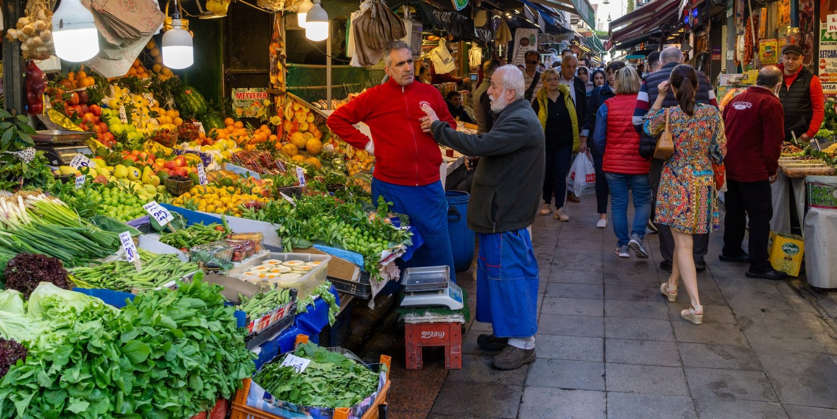 Two men talking to each other at a farmers market abroad