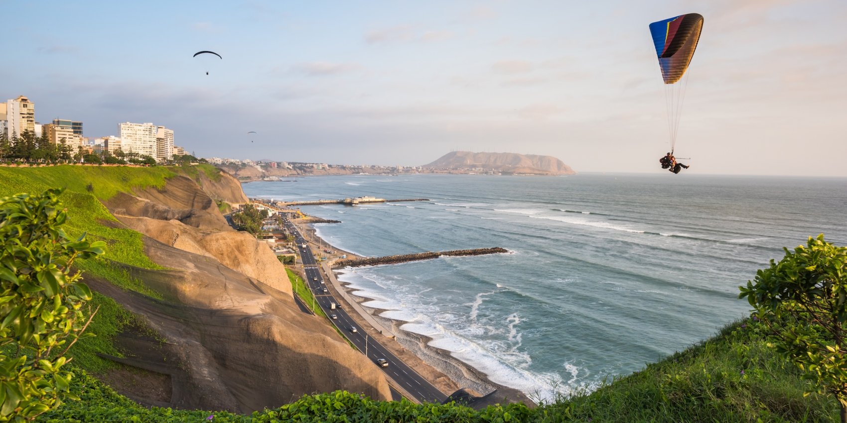Paragliders flying over the ocean and coastline of the Malecón in Lima, Peru.
