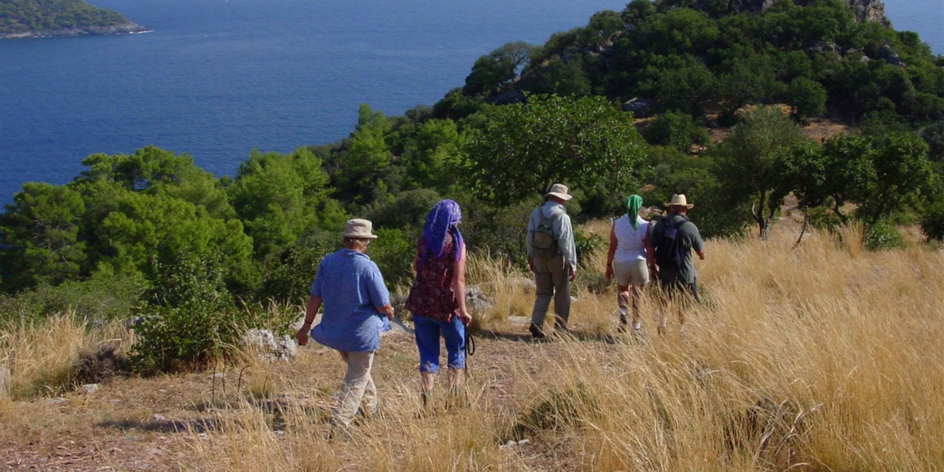 A group of people walking on a grassy hillside overlooking the Carian Coast in Turkey