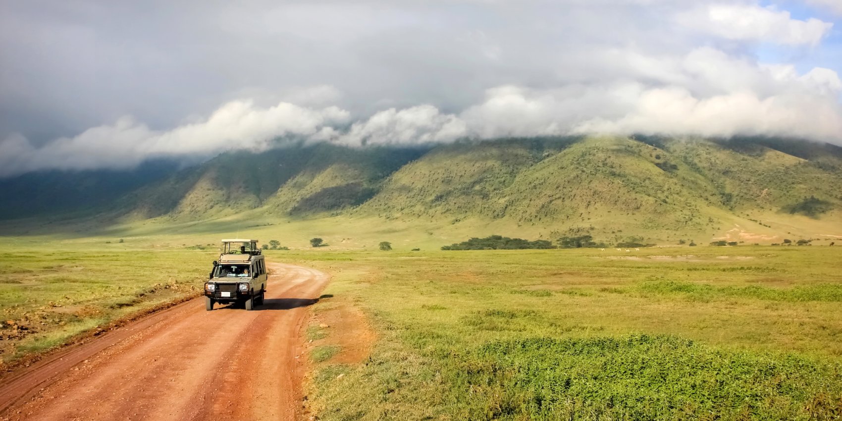 A safari vehicle drives through Ngorongoro Conservation Area, showcasing the low-impact approach of eco-friendly African safari tours in protected environments