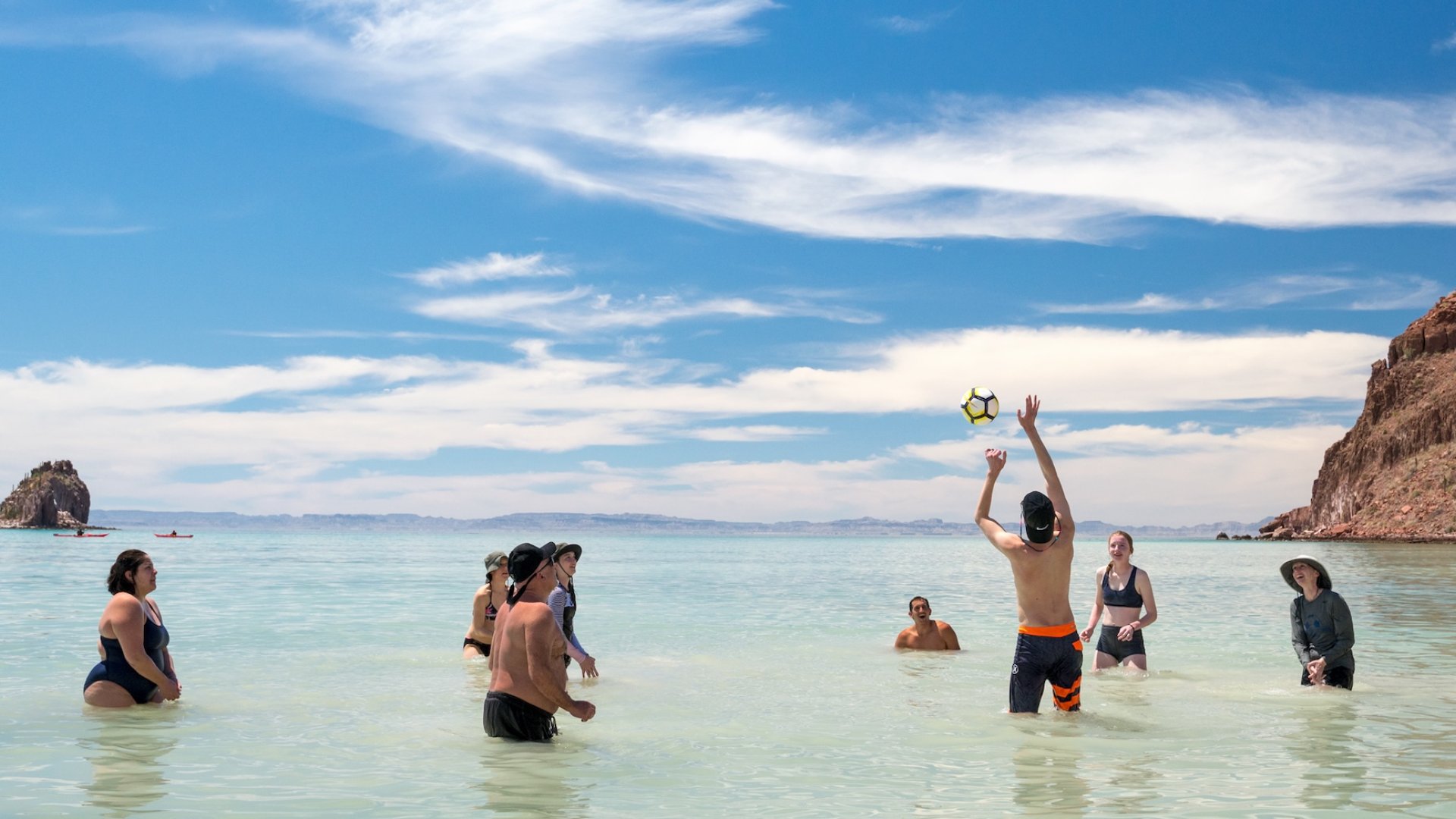 A group of teens playing volleyball in the Gulf of California on a family beach vacation in Baja.