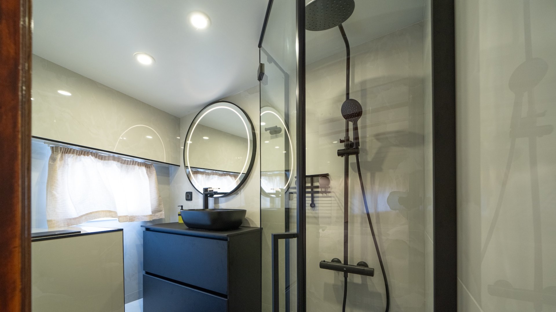 Modern style bathroom inside of luxury Croatian yacht with a round mirror and shower.
