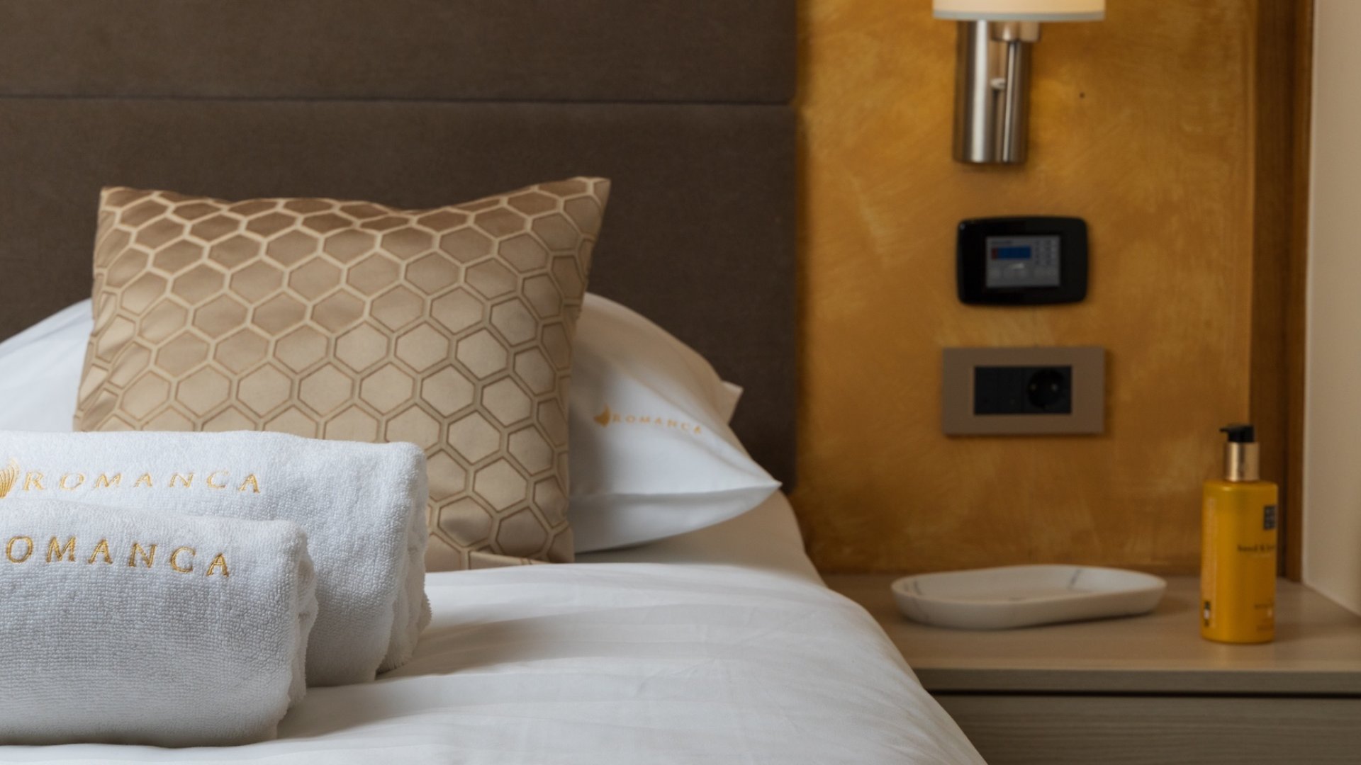 A neatly made bed in a yacht cabin with towels, pillows, and a bedside table.