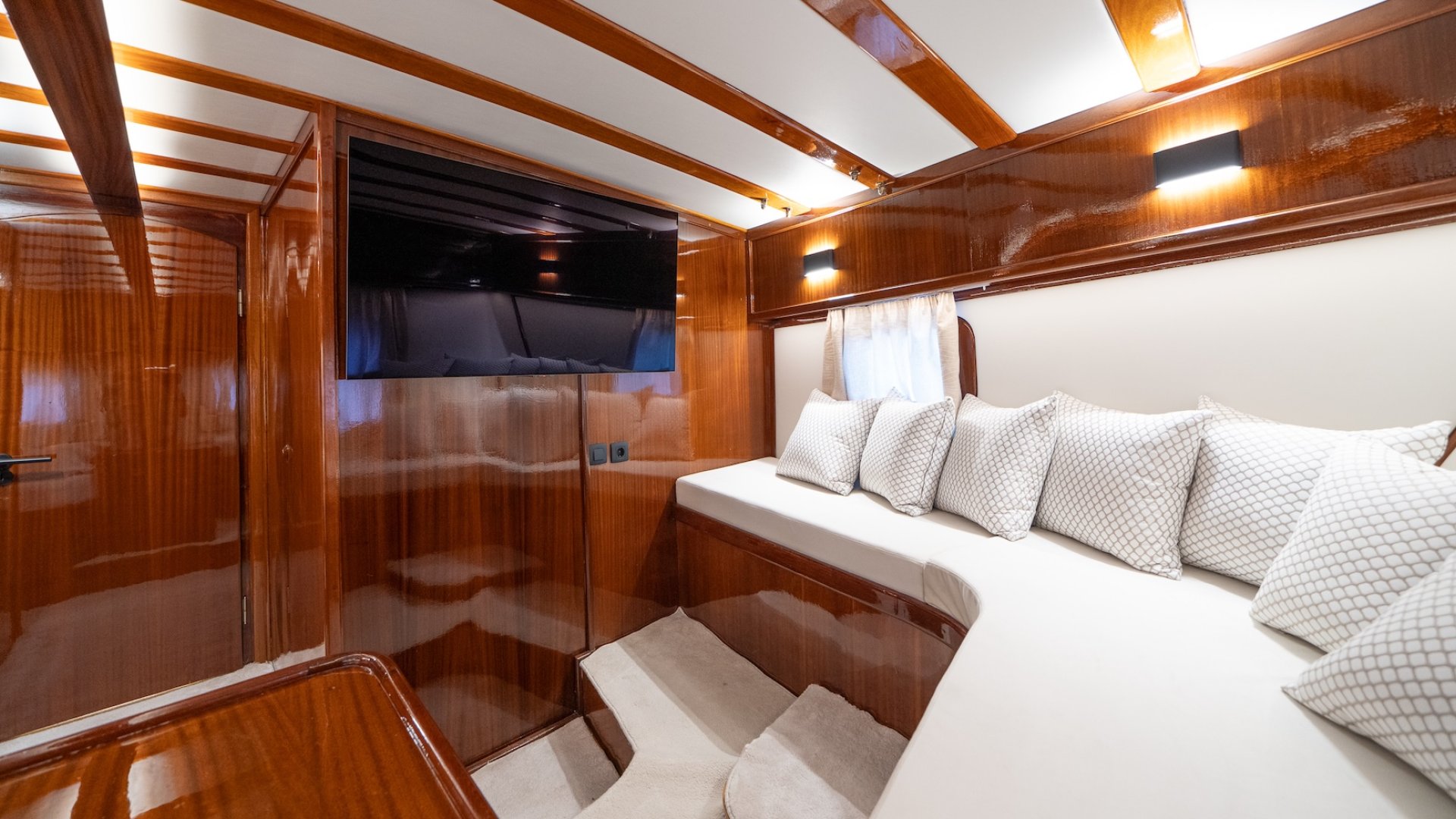 Interior cabin on a yacht with a lounge area and TV.