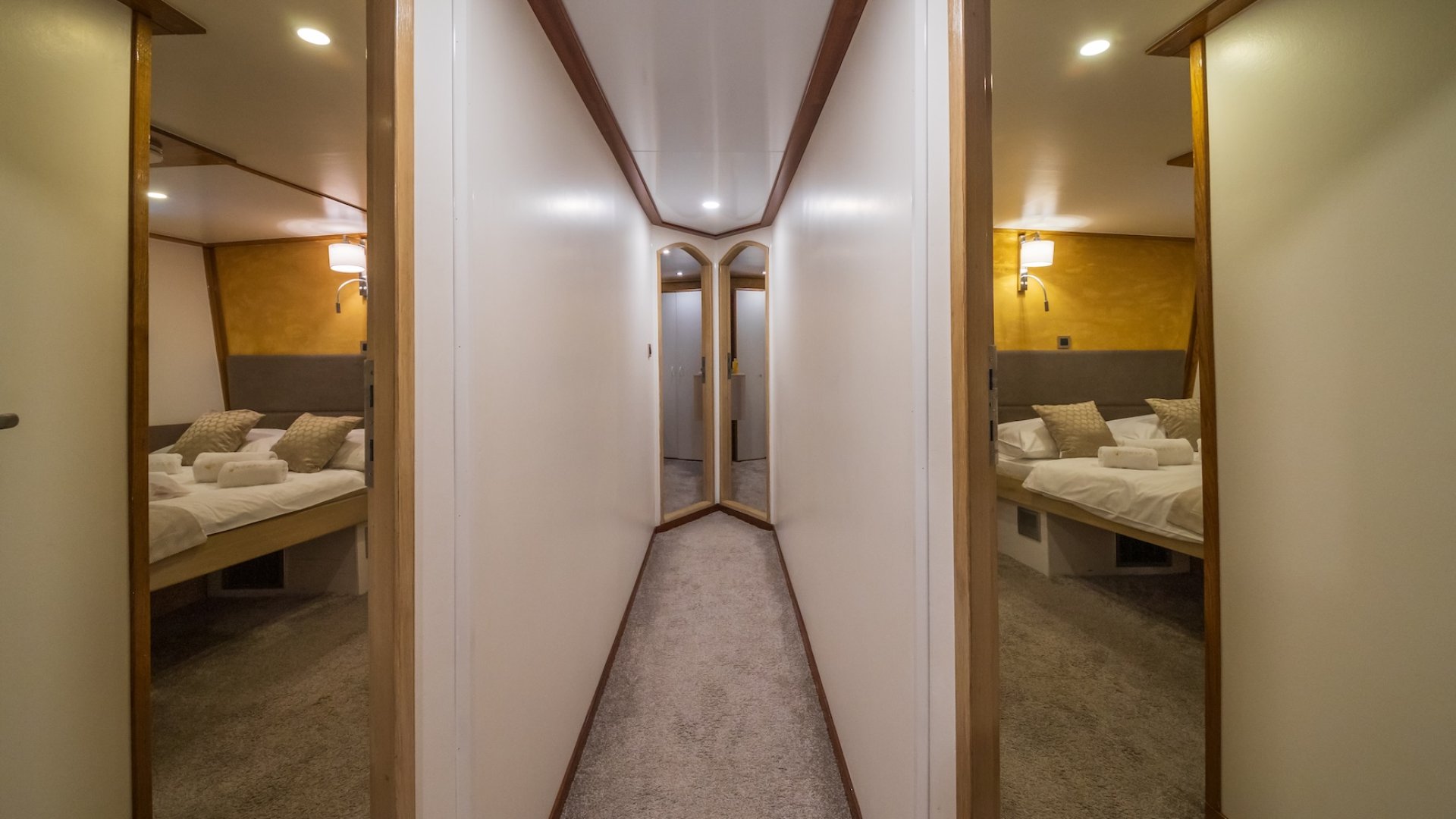 The hallway inside of a yacht with four open doors leading to spacious cabins.