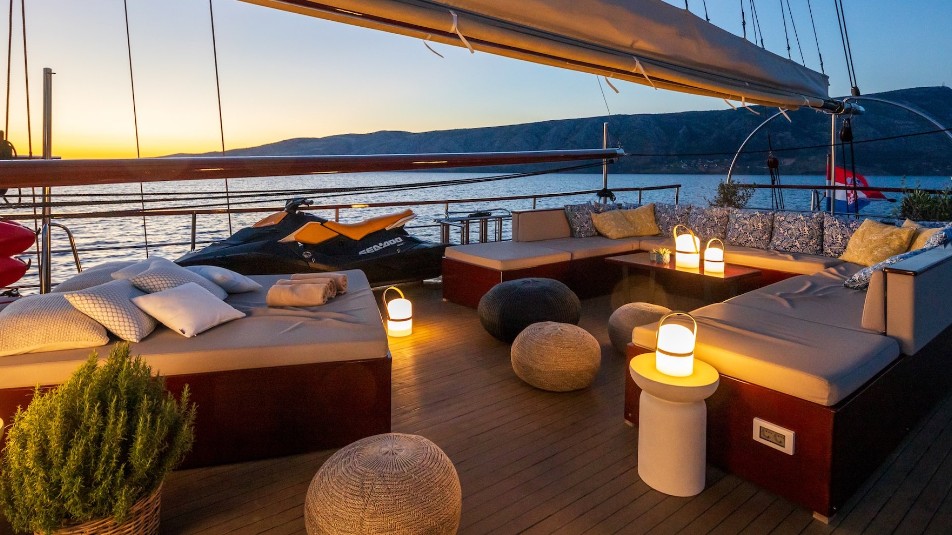 A yacht's sun deck at dusk with a view of the Adriatic Sea and mountains in the background.
