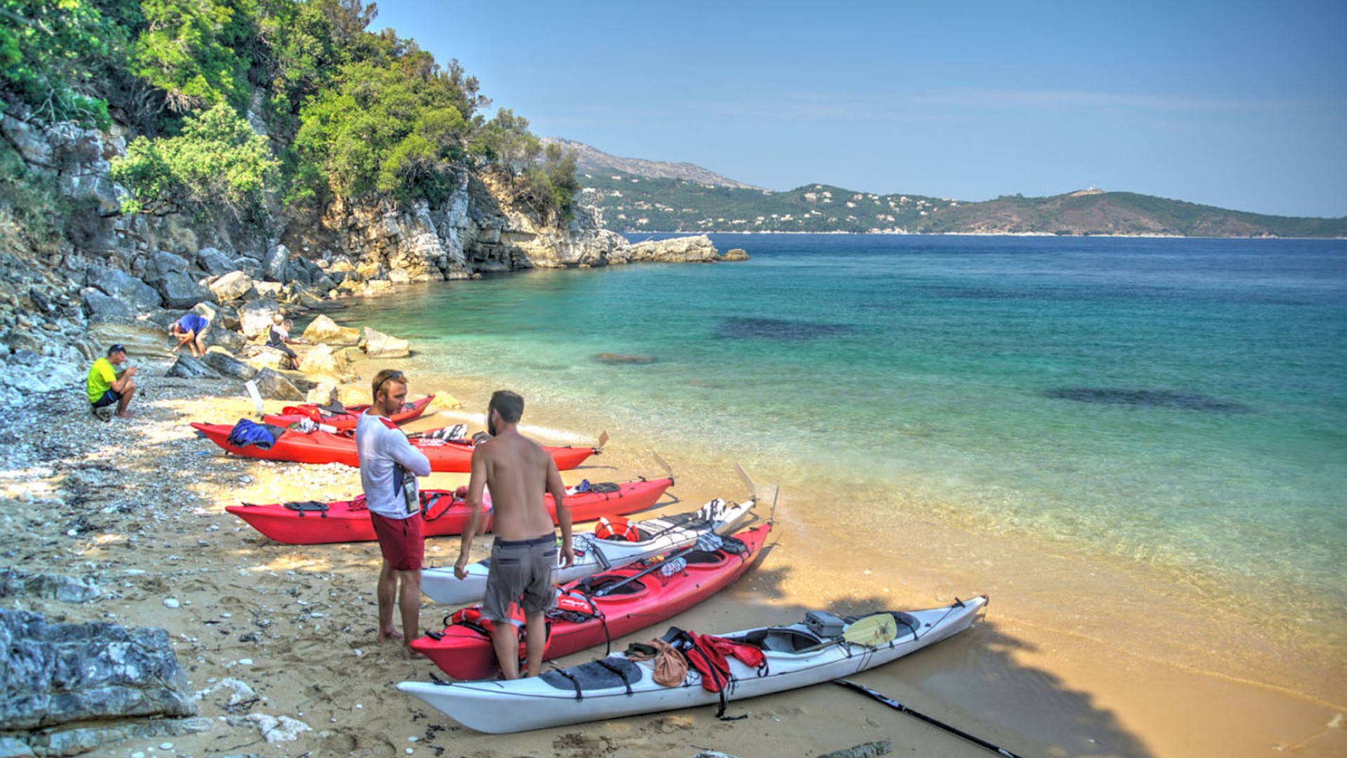 Sea kayaks pulled up on the shore on a rocky beach on a sunny day in Croatia
