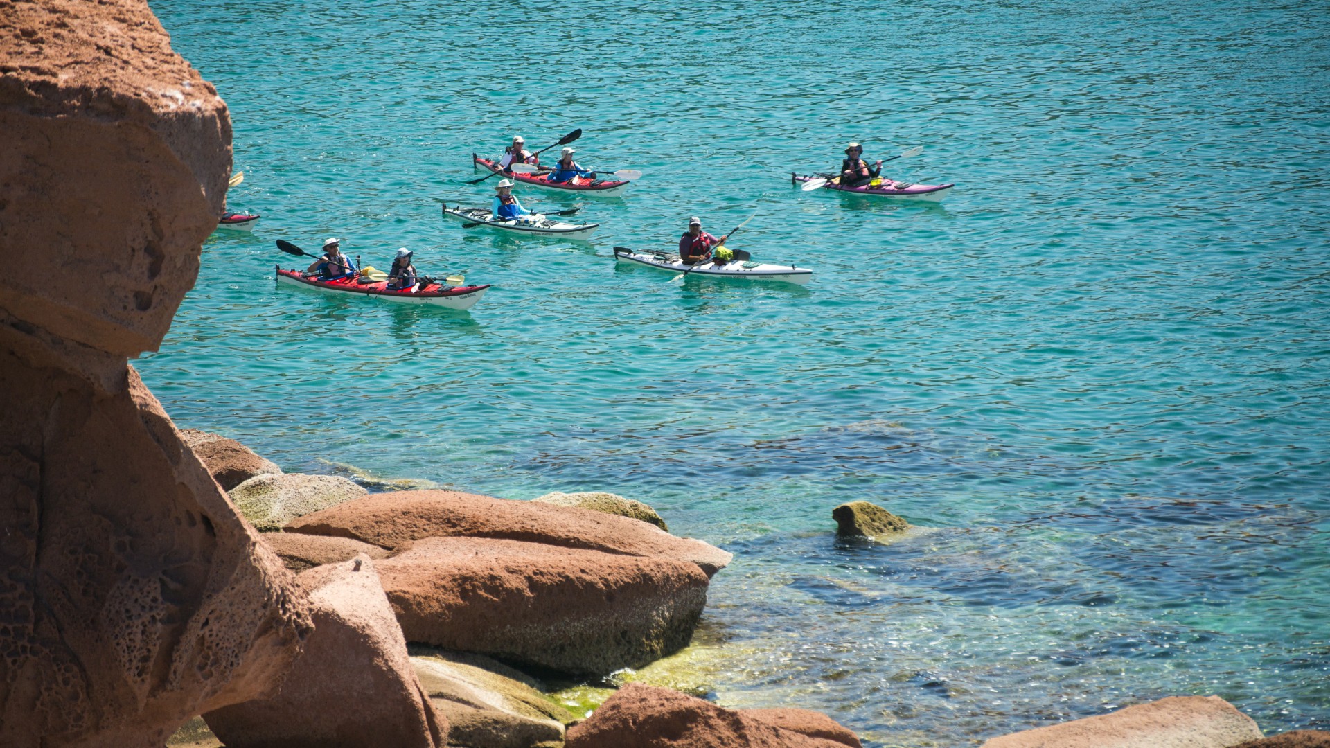 Group of sea kayakers paddling around a bend off the coast of La Paz on the Sea of Cortez