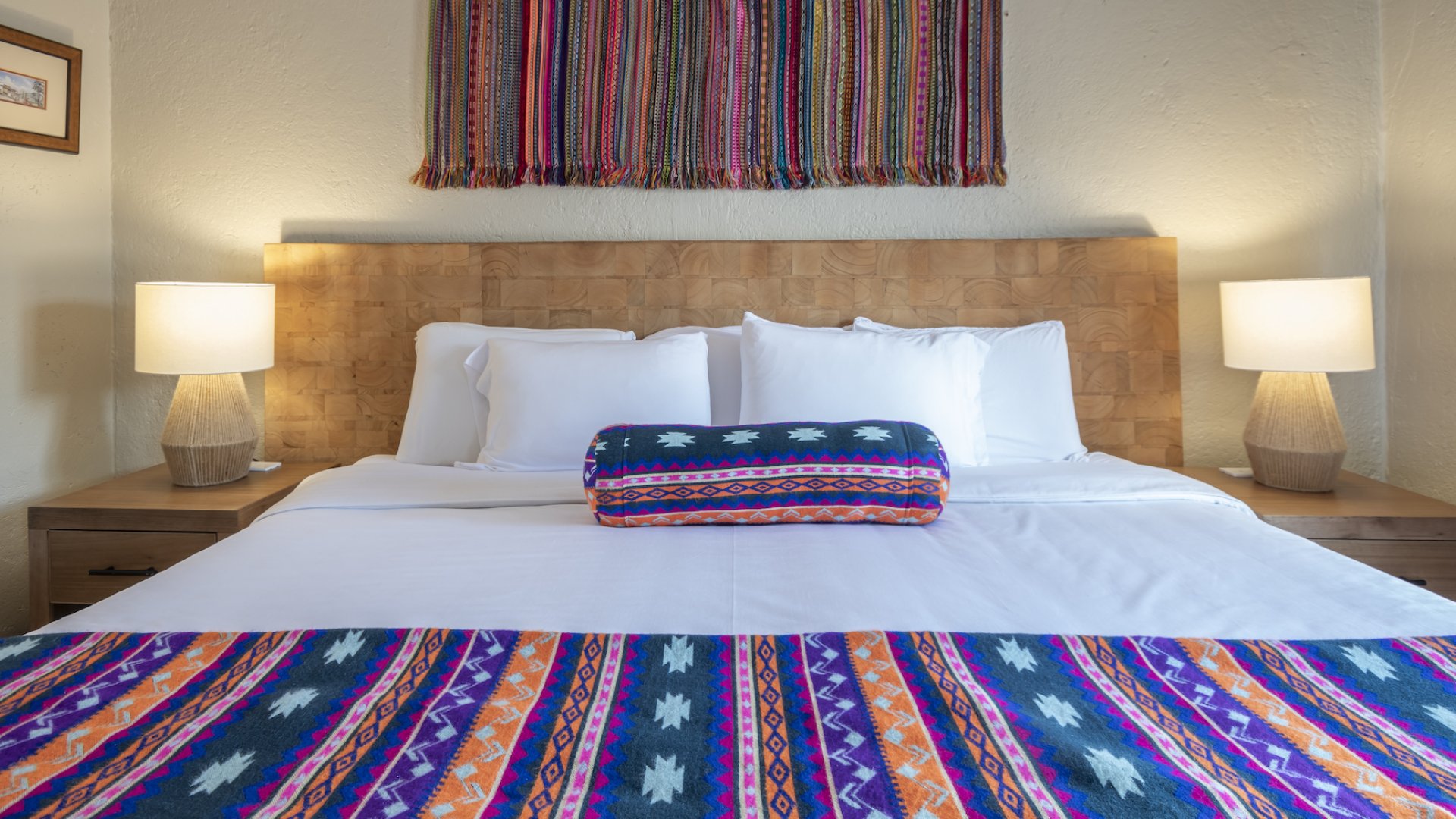 Cleanly made colorful bed full of Peruvian woven textiles