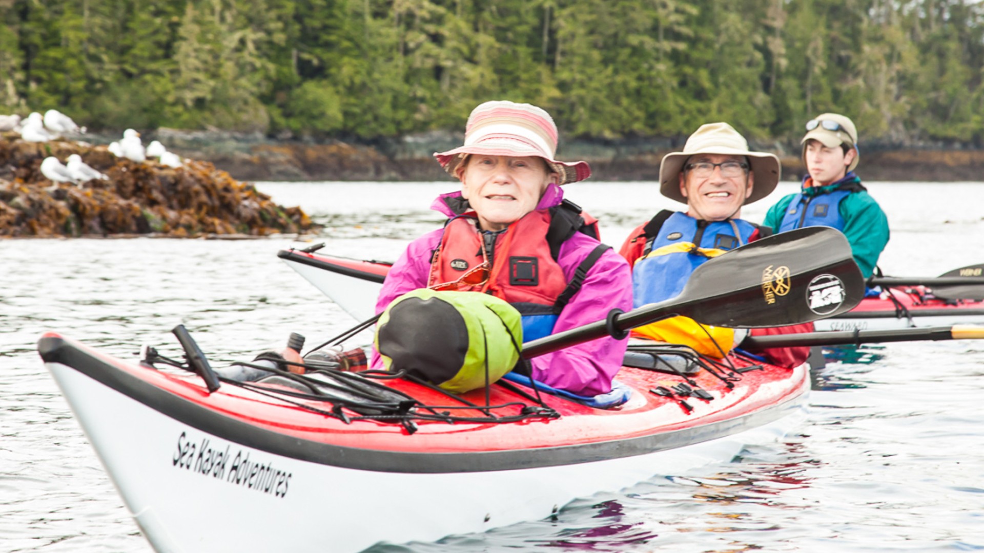 People in a tandem sea kayak smiling in the Johnstone Strait off the coast of Vancouver Island