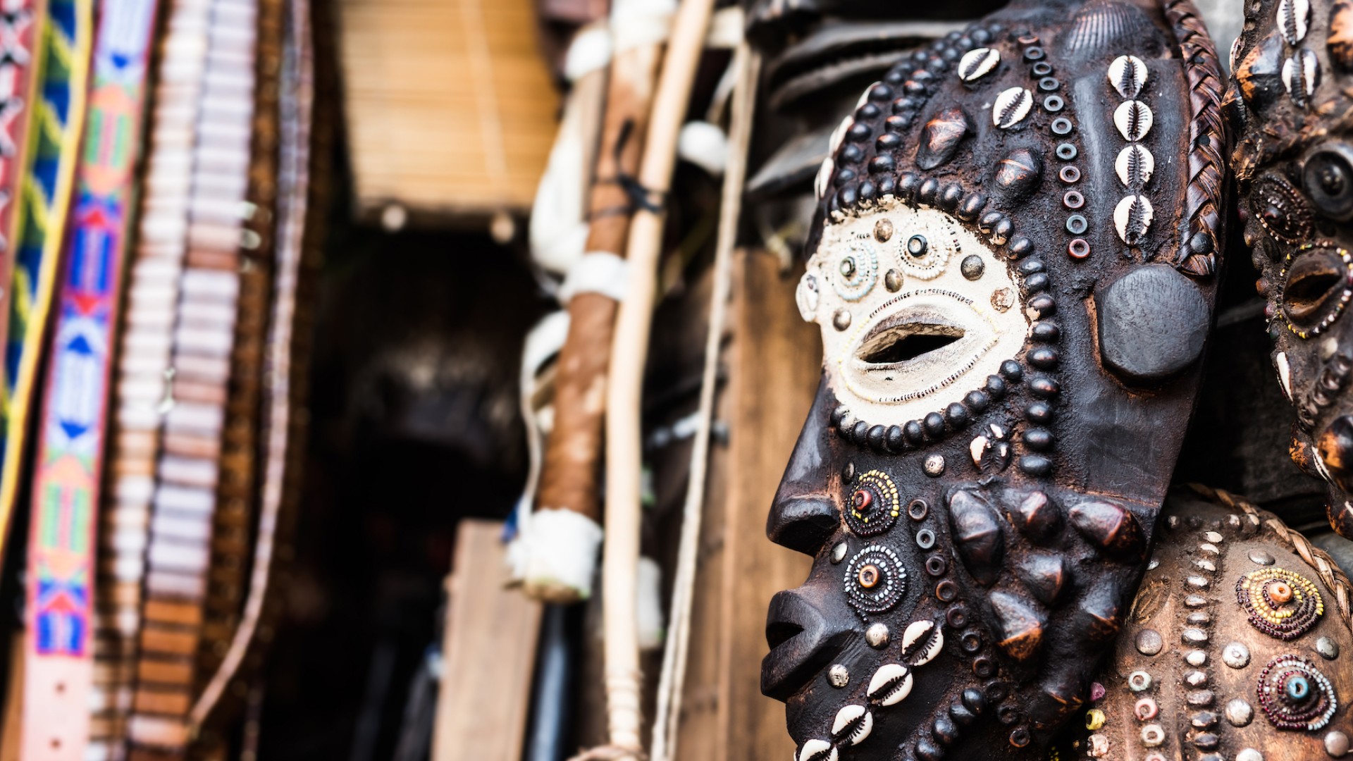 A detailed ceramic face mask next to various beaded necklaces of traditional style in Tanzania