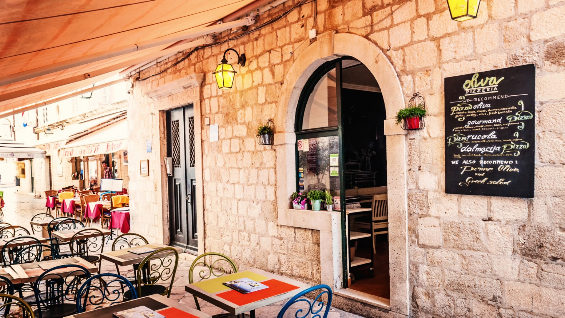 The outside of a brick restaurant in Dubrovnik with plenty of outdoor seating