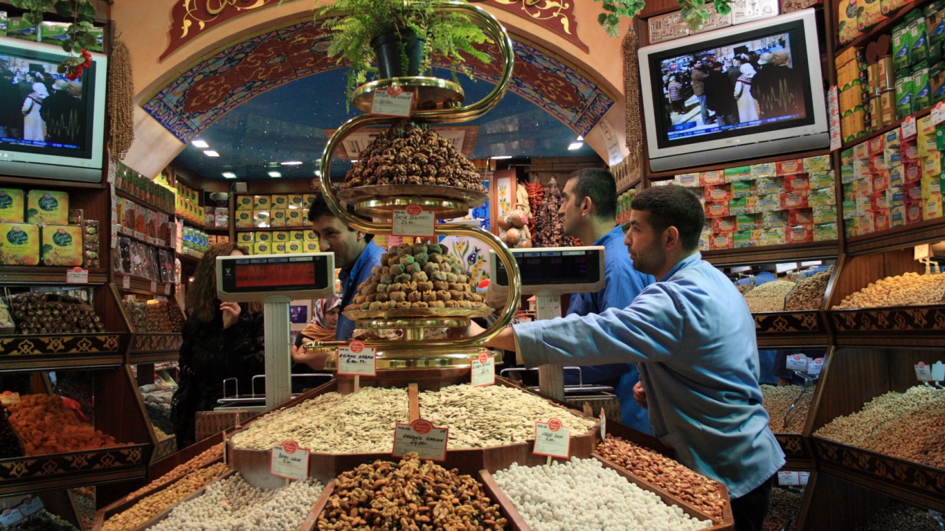 A man pouring bulk goods onto a shelf in a classic Turkish market full of bulk dry goods and spices