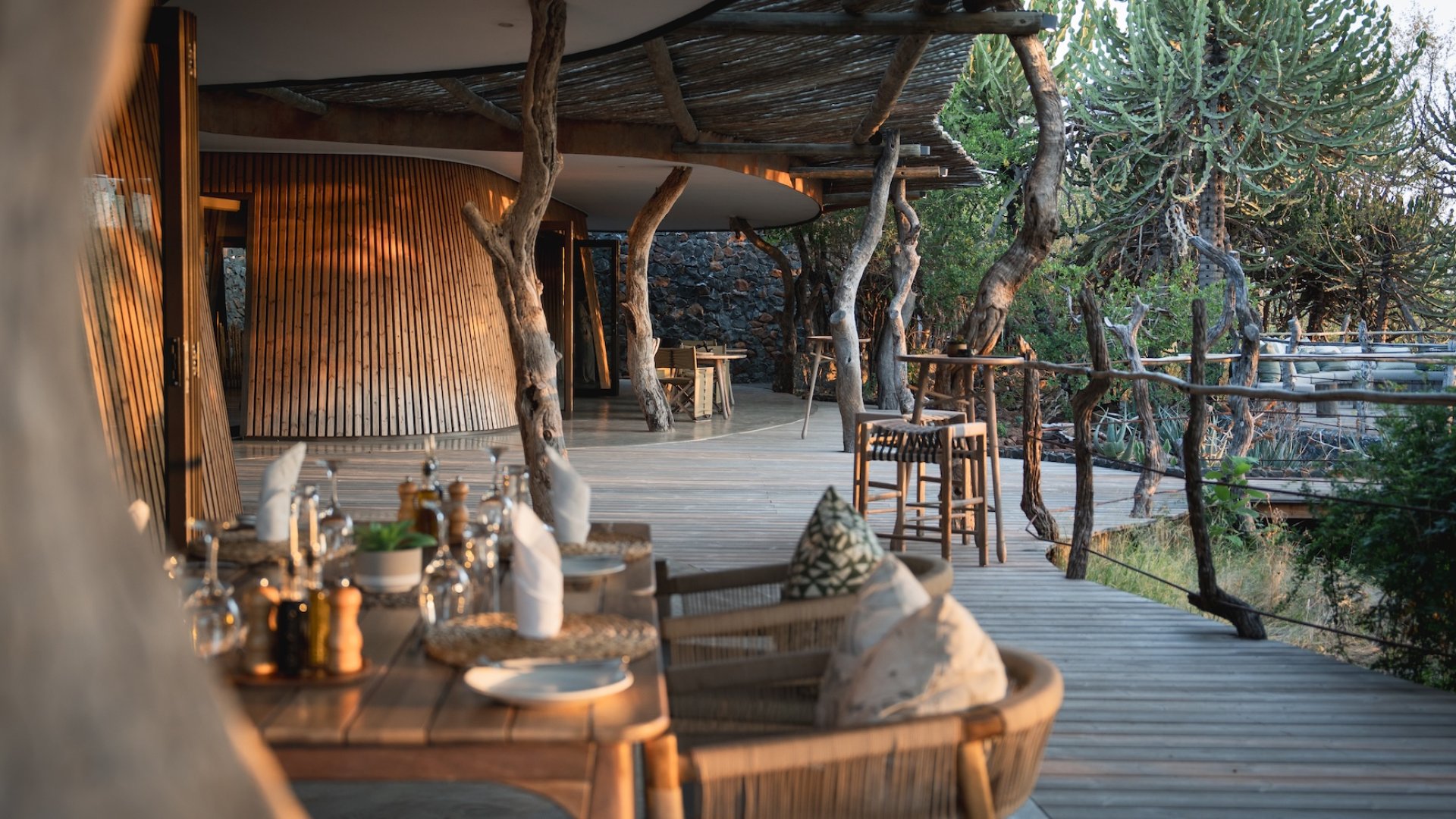 Open-air lodge dining area with wood accents and views of surrounding trees in Botswana.