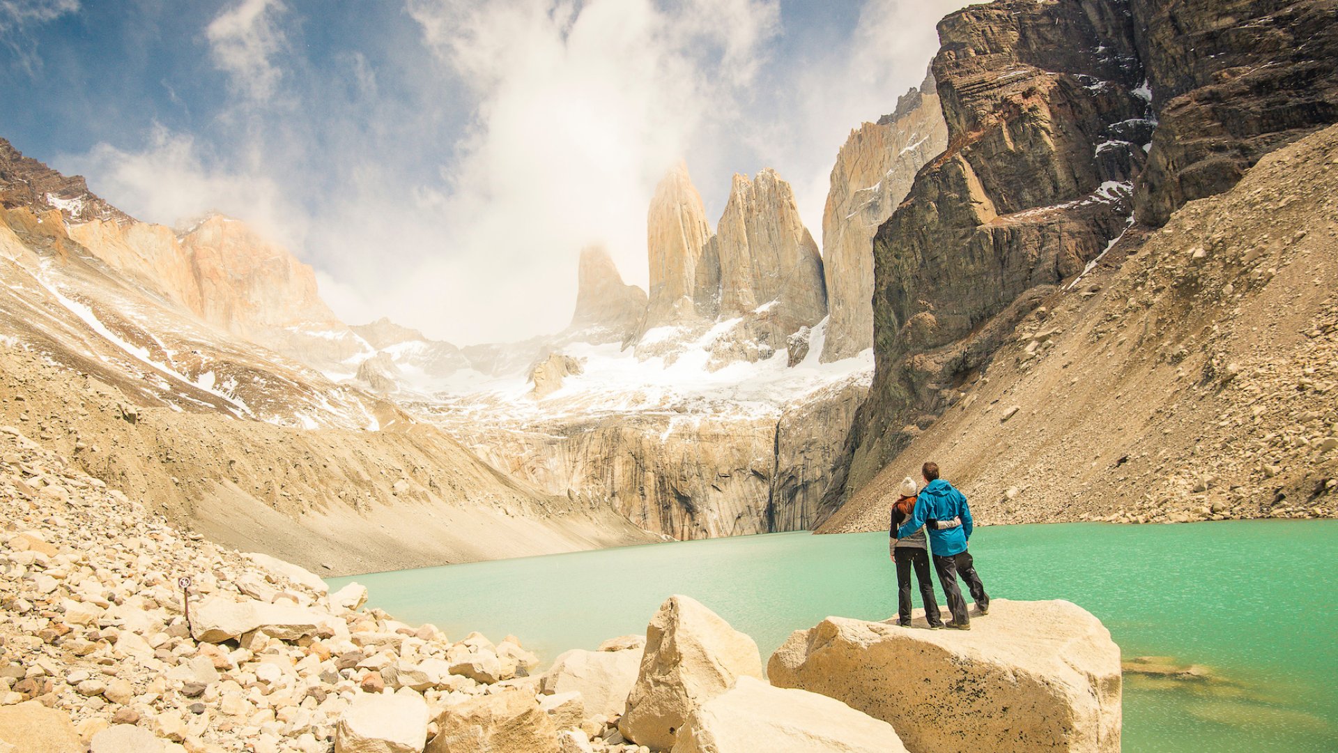 A couple posing for a photo in front of the Fitz Roy mountain range in Patagonia