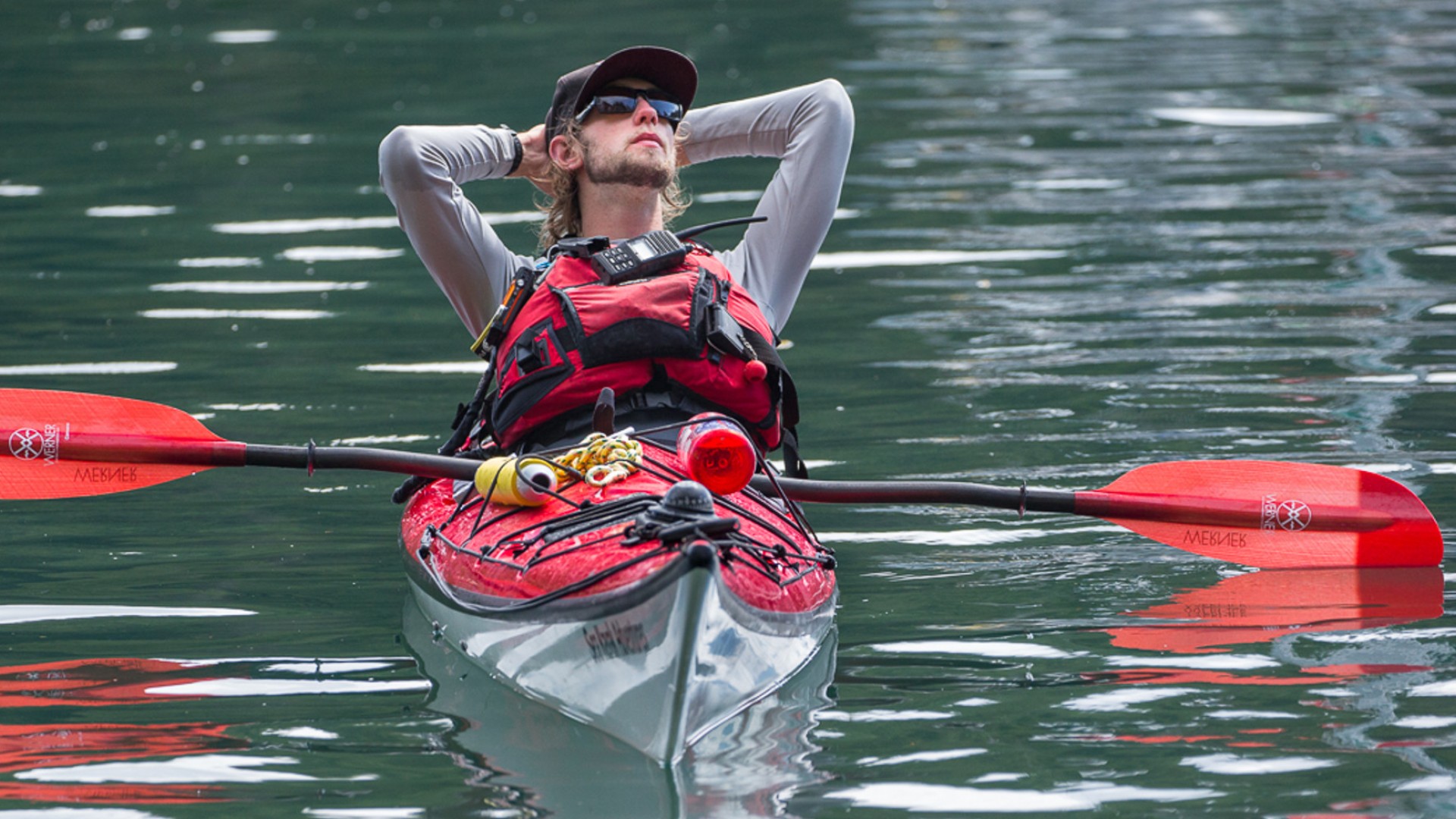 Person in a single kayak with their hands behind their head looking to the sky