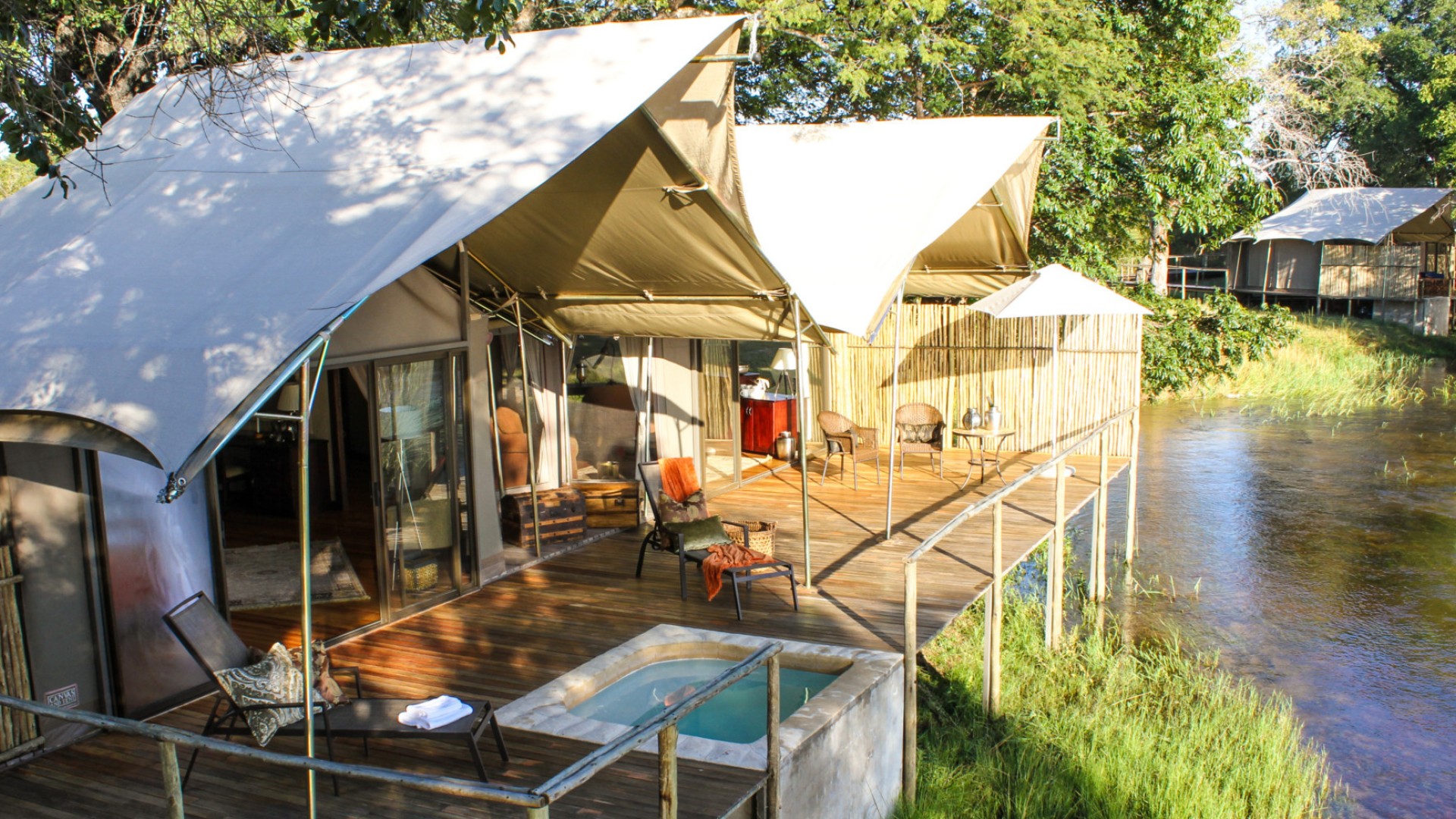 The outside of a safari style suite with chairs on a deck and small built in hot tub