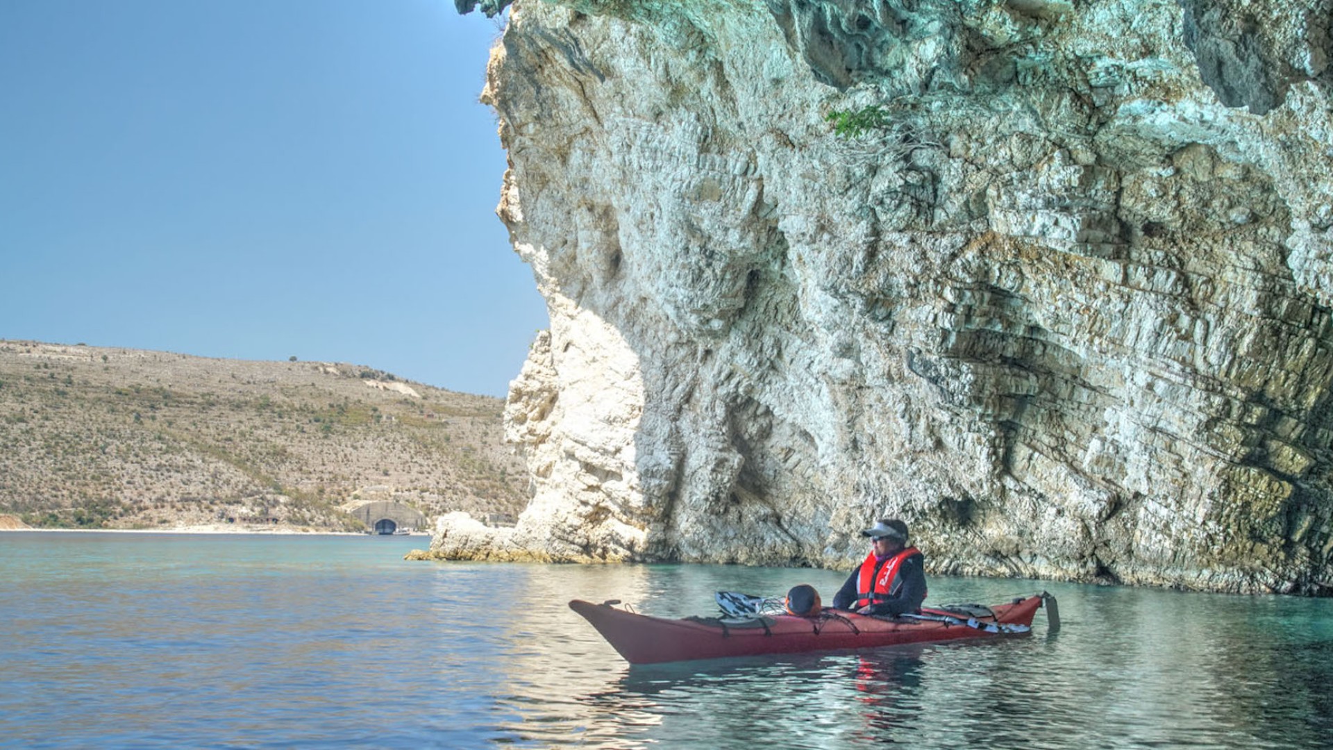 Sea kayaker paddling through a limestone cave overhead in Europe on a sunny summer day