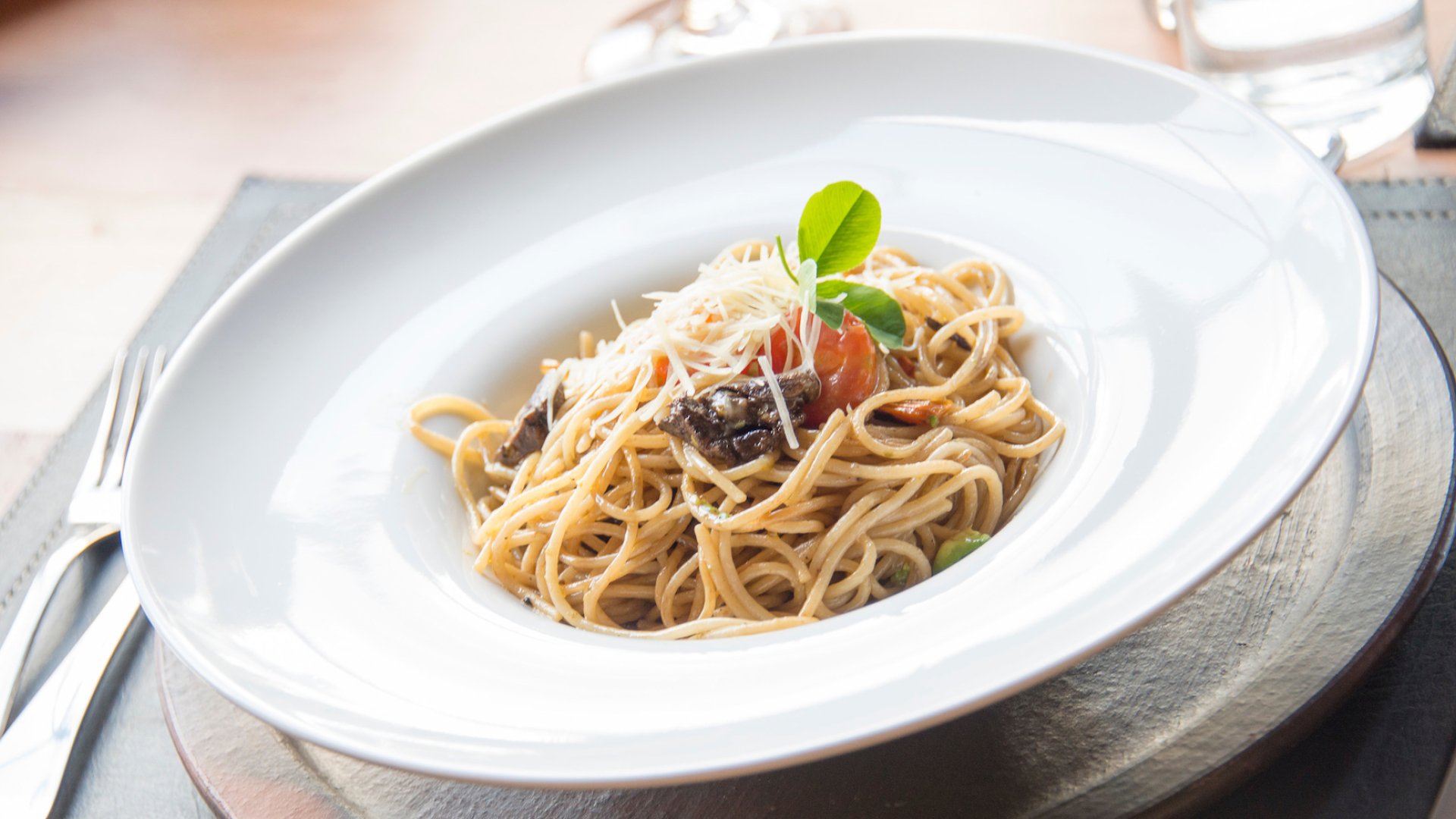 A white bowl of pasta on a nice place setting