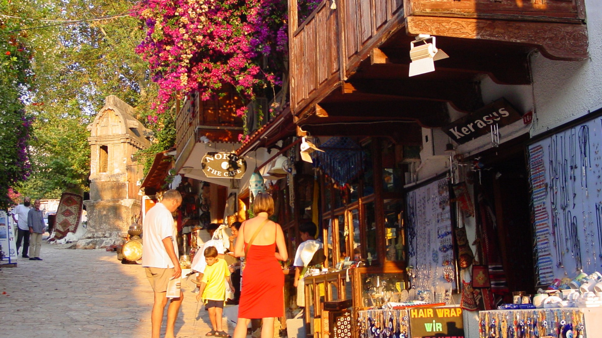 Parents with their child walking the cobblestone streets of Turkey next to a local art mercantile around sunset