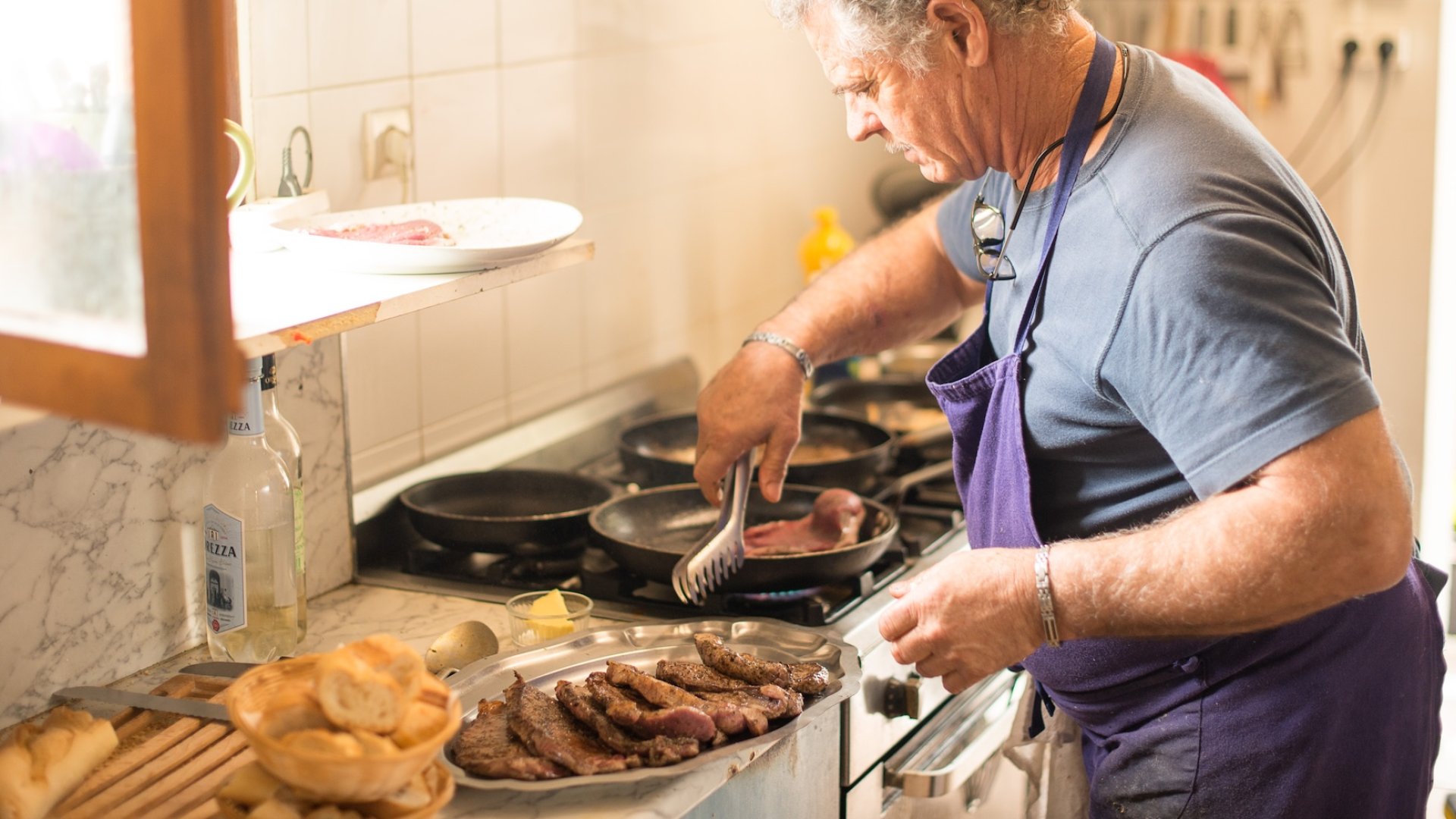 Corsican chef preparing traditional meat dishes during a locally hosted tour experience in Corsica.
