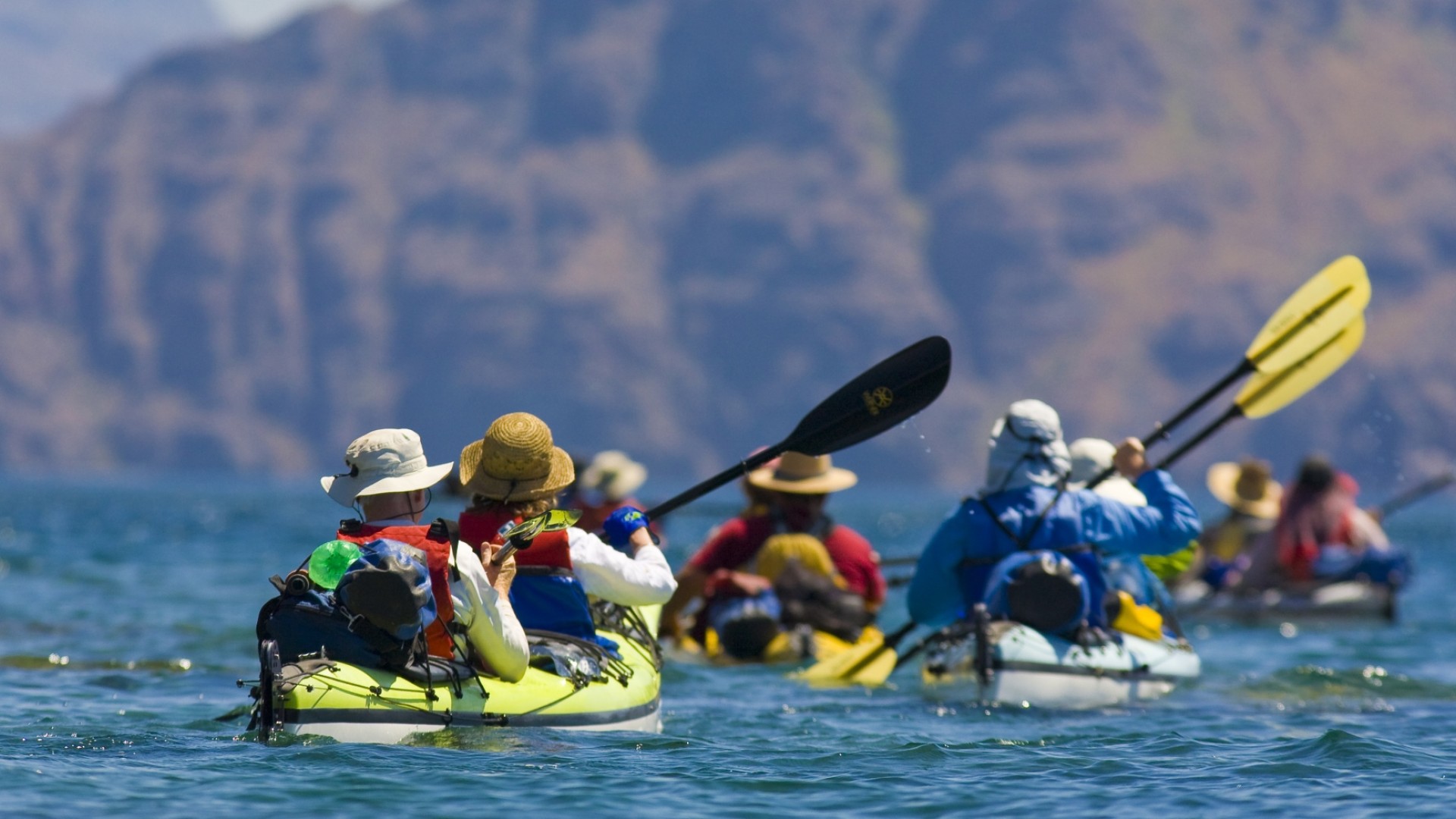 Group of kayakers form behind paddling towards Danzante Island in Loreto Bay, Mexico