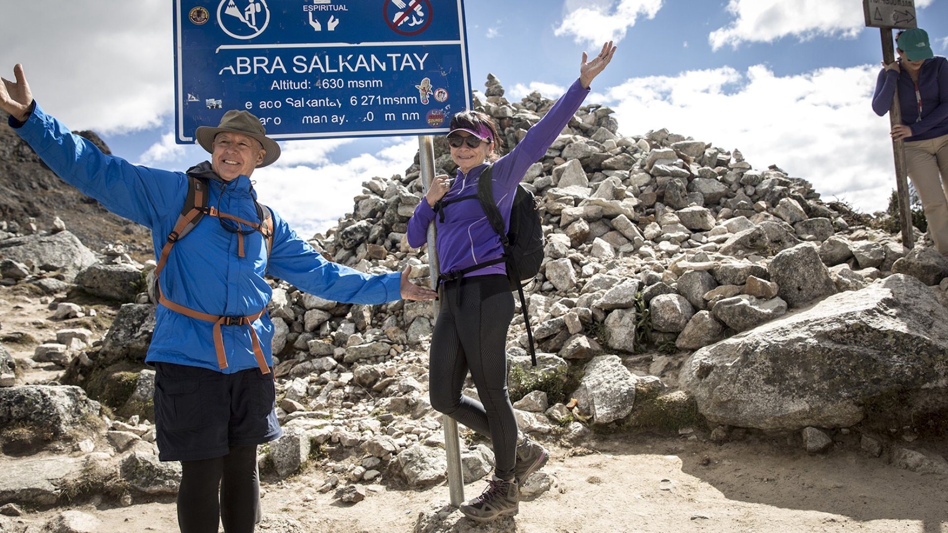 Happy hikers celebrate reaching Abra Salkantay Pass at 4,630 meters in the Peruvian Andes.