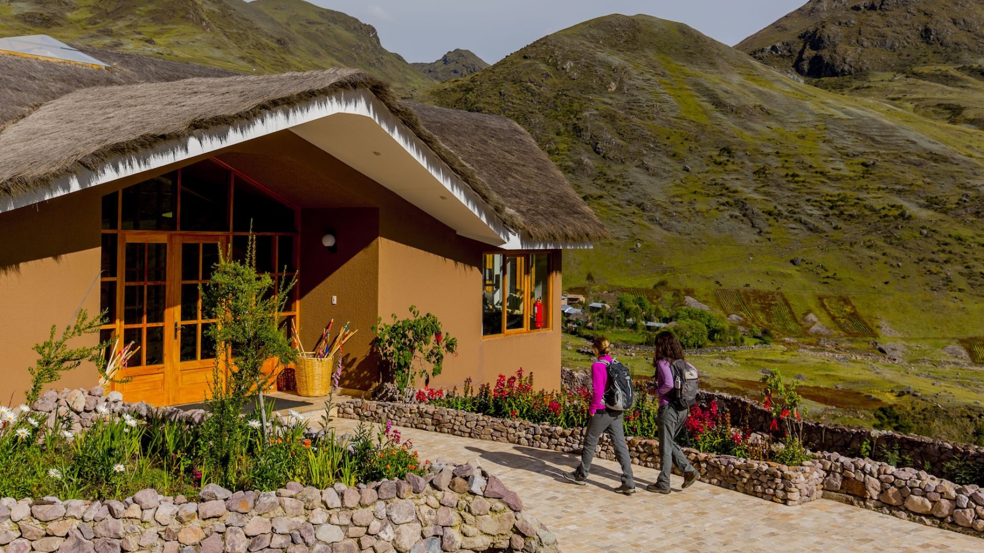 Two hikers arrive at a scenic Peru lodge in the Sacred Valley, surrounded by lush Andes mountains.