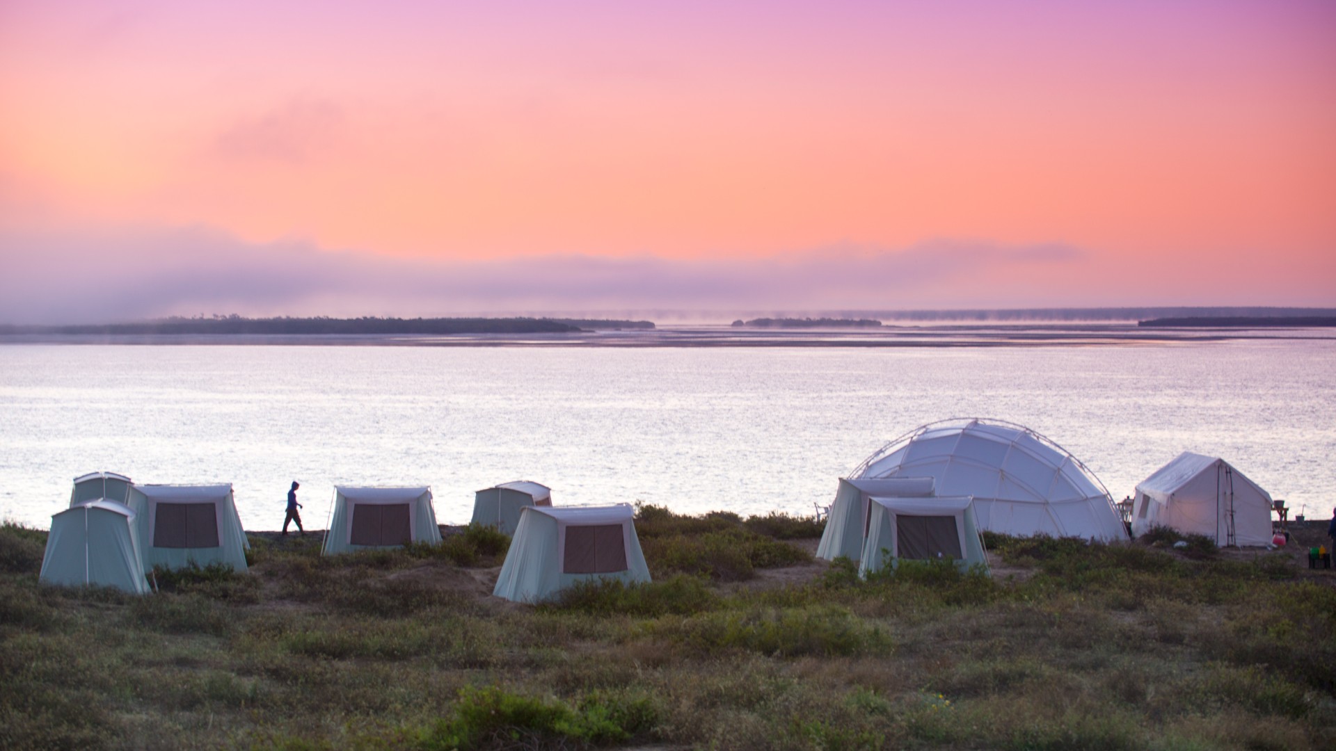 Sunset over canvas tents set up on a beach