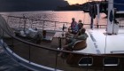 Group of tourists sitting on the bow of a yacht at sunset.