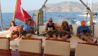 A group of people lounging under a shaded deck at the back of a small yacht in Turkey