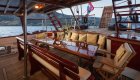 An outdoor dining area on a yacht with a wooden table and cushioned seating.