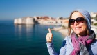 A woman wearing sunglasses smiling in the right third of the image in front of Adriatic Sea in Croatia