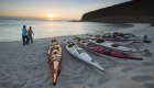 Person walking past a group of kayaks pulled up on the shore of Isla Espiritu Santo off of La Paz