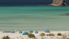 Tents sprawled out on a vast sandy beach with the turquoise Sea of Cortez behind