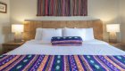Cleanly made colorful bed full of Peruvian woven textiles