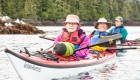 People in a tandem sea kayak smiling in the Johnstone Strait off the coast of Vancouver Island