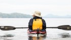 Person looking out onto the ocean while in a sea kayak with their paddle across their lap 