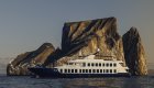 Small ship cruising past Kicker Rock at sunset in the Galapagos
