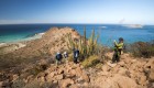 Hiker taking a picture of a large cacti and the surround view from an overlook viewpoint on a hike on Isla Espiritu Santo in Baja California Sur