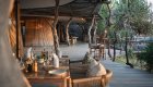 Open-air lodge dining area with wood accents and views of surrounding trees in Botswana.