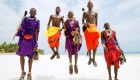 Five Maasai people in traditional garb jumping on sand in Kenya