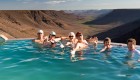 People smiling in a pool overlooking a vast valley in Namibia