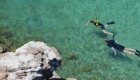 Two people in yellow snorkel masks snorkeling around a sandstone cove in the Gulf of California