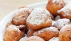 Traditional Croatian Dessert that look like beignets covered in powdered sugar in a white bowl.