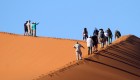 Group of people walking up the arete of a sand dune in Namibia 